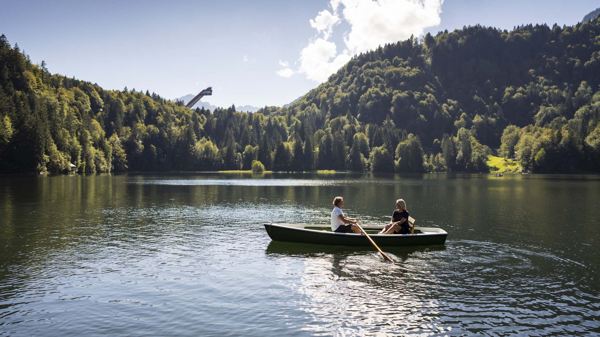 Plant euren Urlaub in Oberstdorf Zwei Personen rudern auf einem See umgeben von Wald und Bergen