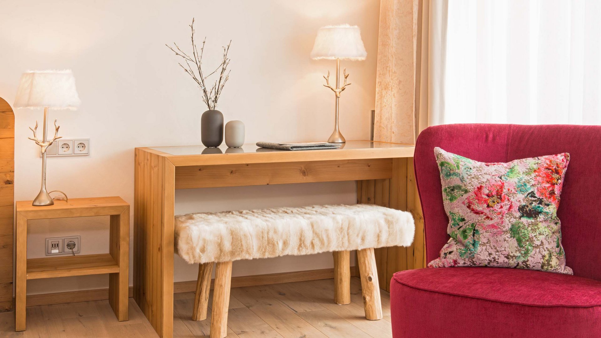 Hotel and holiday apartment in Allgäu, Oberstdorf Cozy living room with red armchair, wooden table, and furry bench