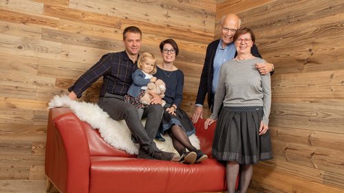 Your feel-good space at our hotel in Oberstdorf, Allgäu Five-person family on red sofa in wooden room