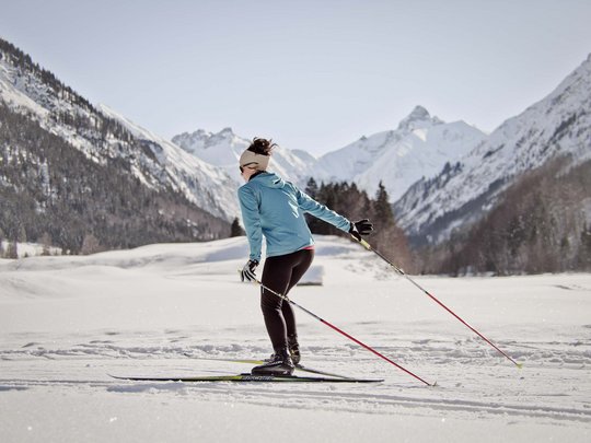 Hahnenköpfle: Ferienwohnung, Lodge und Hotel in Oberstdorf Frau beim Langlaufen in verschneiter Berglandschaft