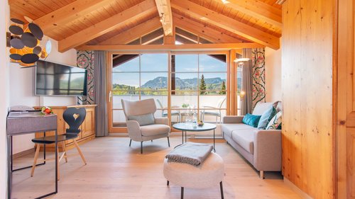 Your feel-good space at our hotel in Oberstdorf, Allgäu Bright living room with wooden ceiling and view of balcony and mountains