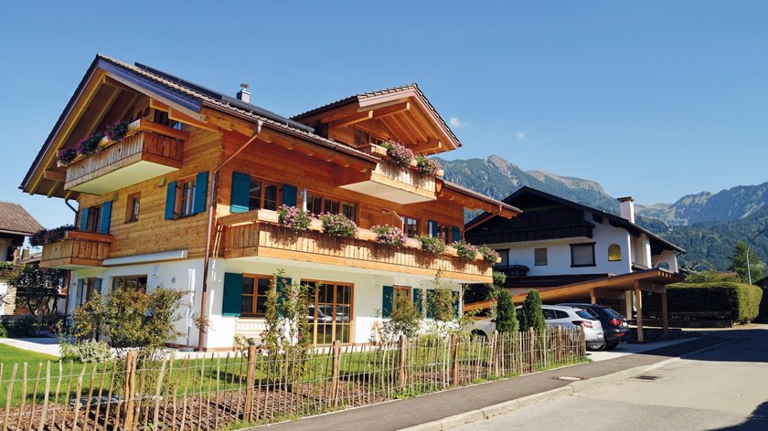 Hotel and holiday apartment in Allgäu, Oberstdorf Modern wooden house with flower balconies in sunny alpine landscape