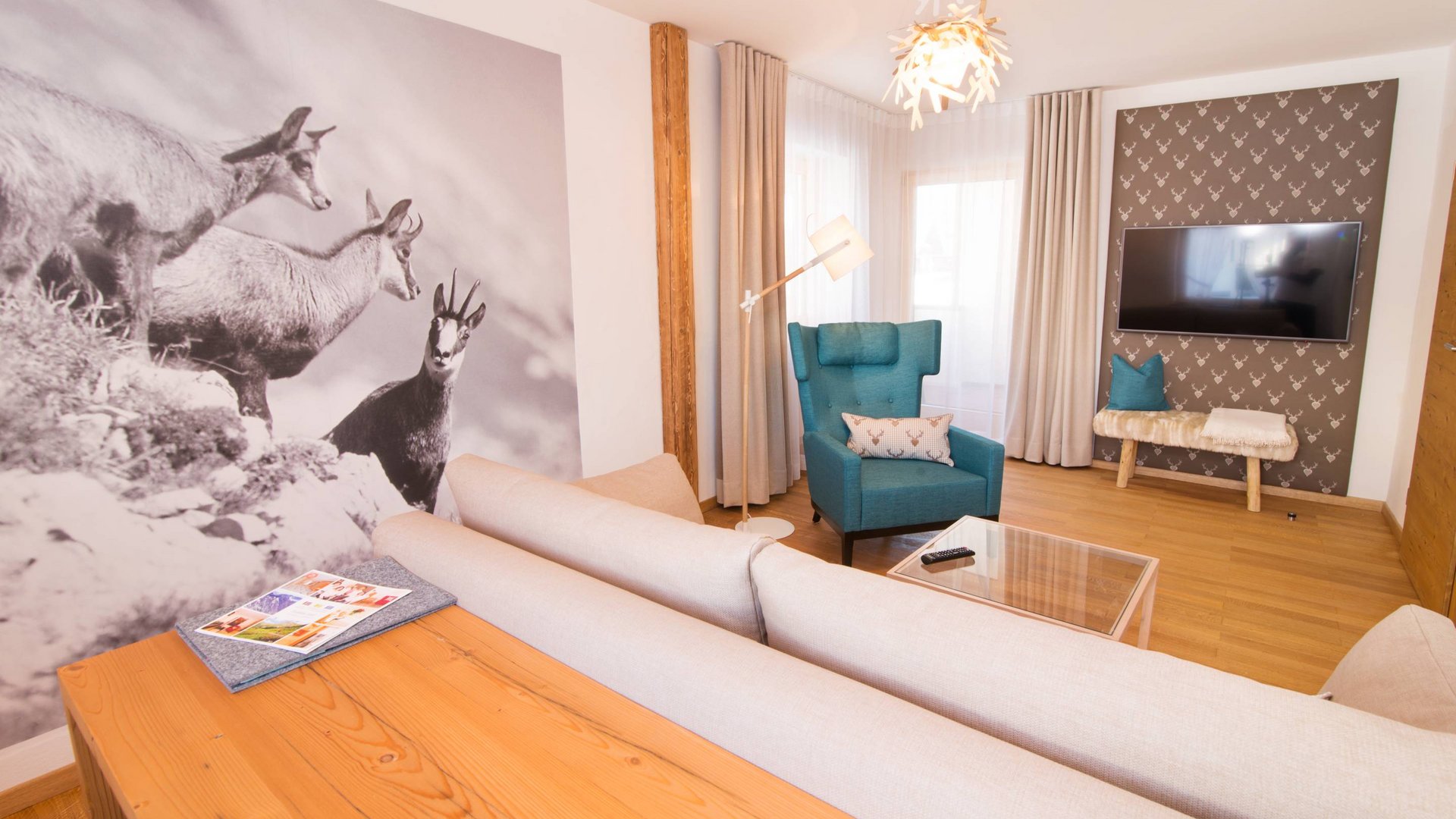 Hotel and holiday apartment in Allgäu, Oberstdorf Modern living room with sofa, armchair, and chamois wall art