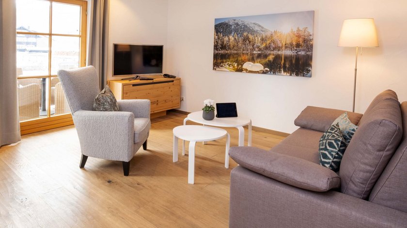 Hotel and holiday apartment in Allgäu, Oberstdorf Cozy living room with sofa, armchair, TV and picture on the wall