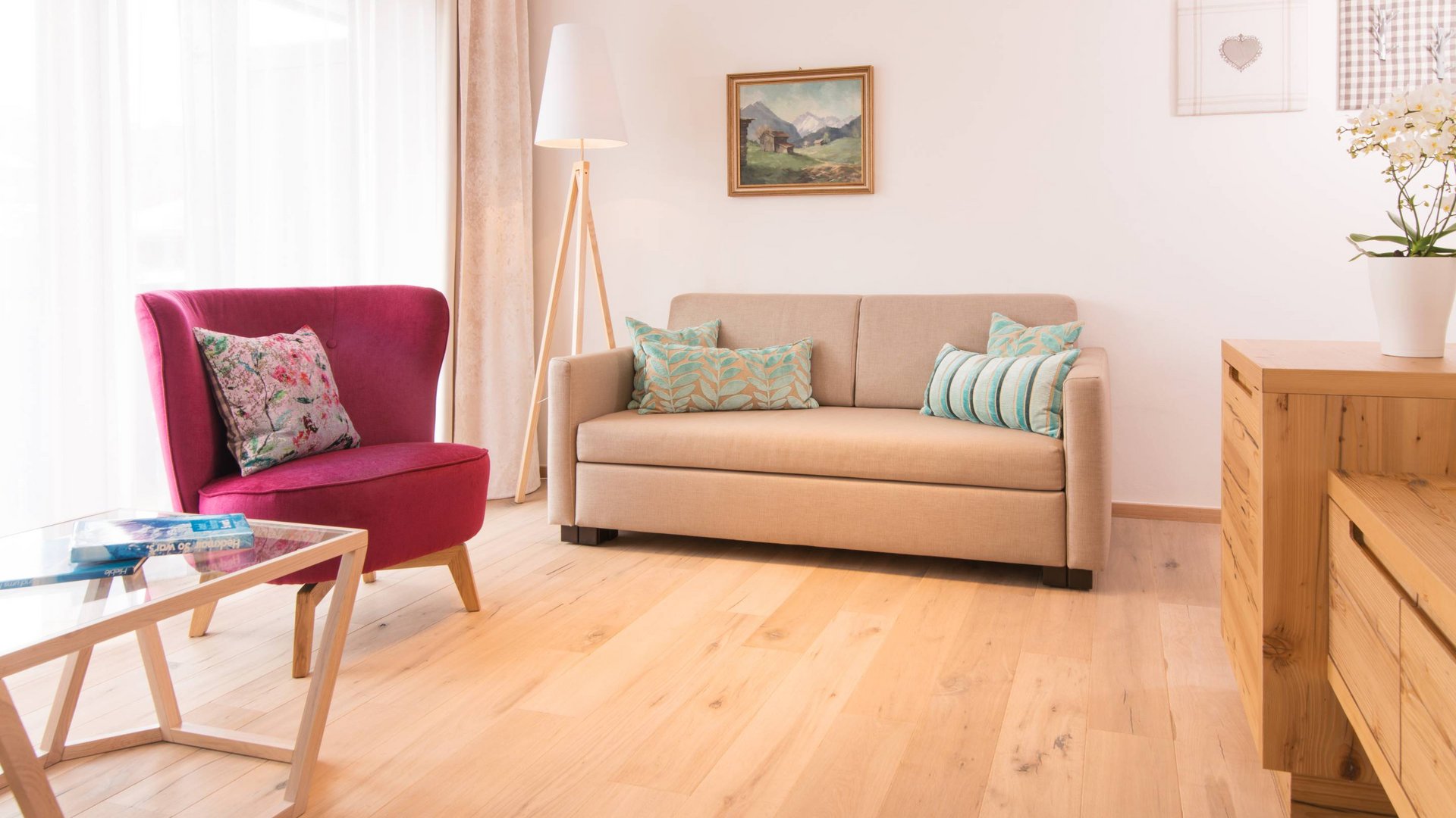 Hotel and holiday apartment in Allgäu, Oberstdorf Modern living room with red armchair, beige sofa and wooden floor