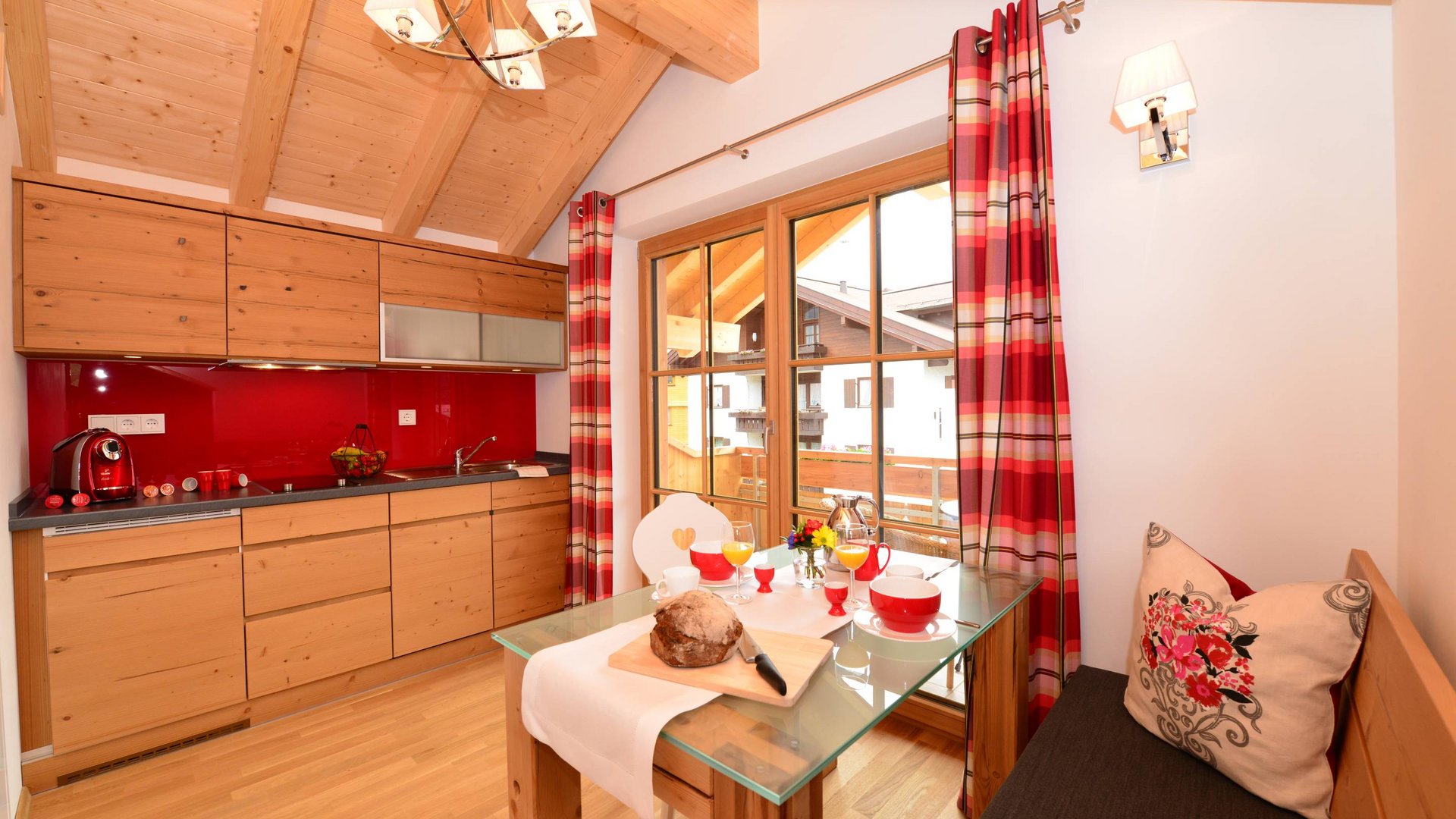Hotel and holiday apartment in Allgäu, Oberstdorf Cozy small kitchen corner with wooden cabinets and red checkered curtains.